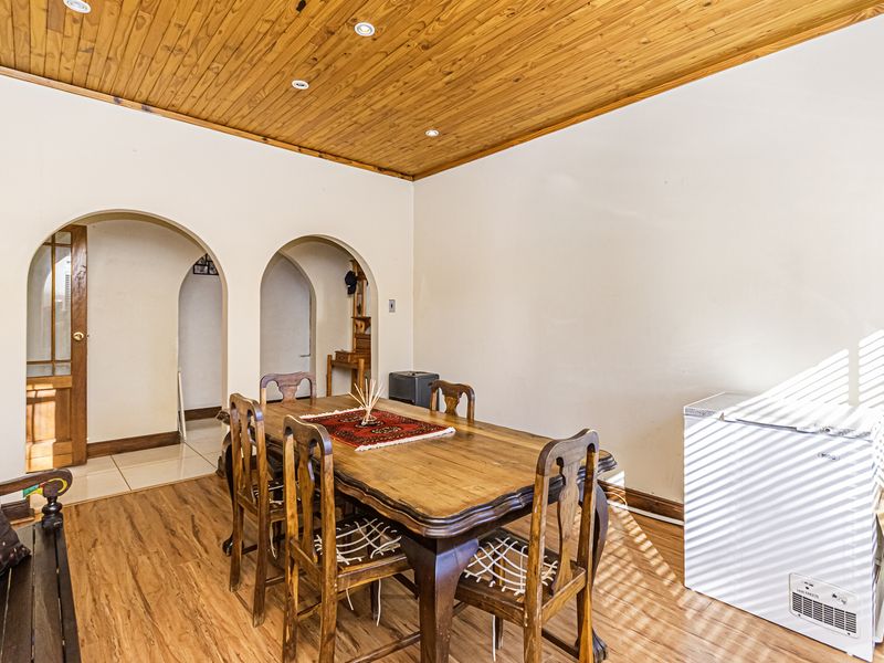 Dining room featuring a warm timber-paneled ceiling, recessed lighting, and distinctive arched doorways leading to adjacent living spaces.