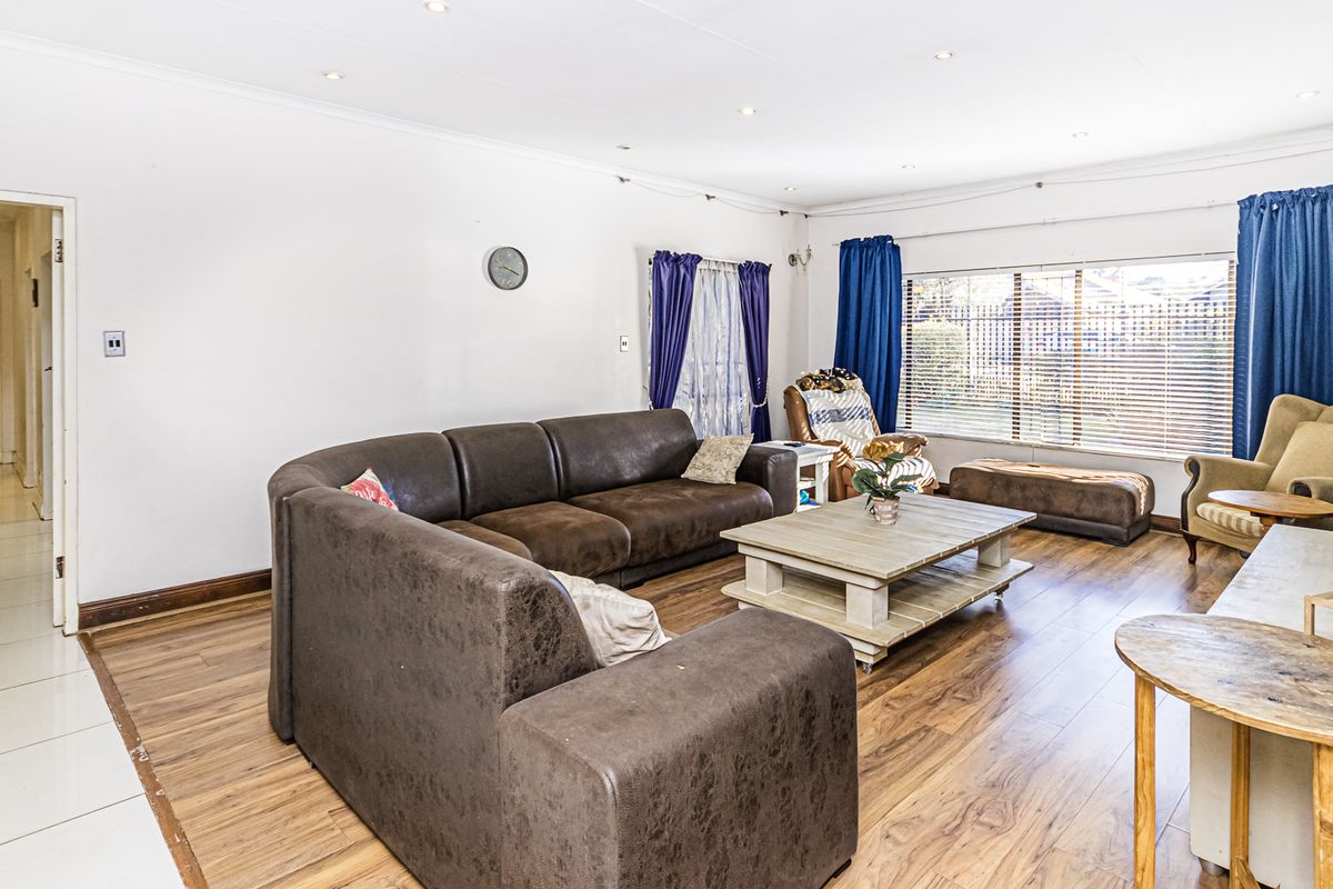 Spacious living room featuring laminate flooring, recessed downlighting, and large windows allowing for ample natural light.