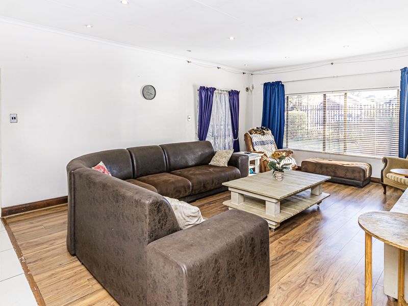 Spacious living room featuring laminate flooring, recessed downlighting, and large windows allowing for ample natural light.