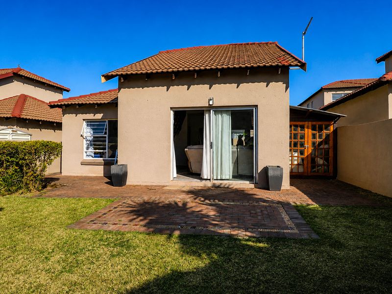 Rear view of the townhouse featuring a paved patio area, sliding glass doors, and a small private garden.