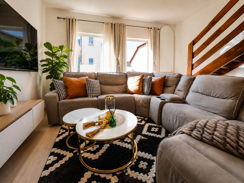 A well-lit living room featuring modern laminate flooring and a timber staircase, creating a warm and inviting atmosphere.