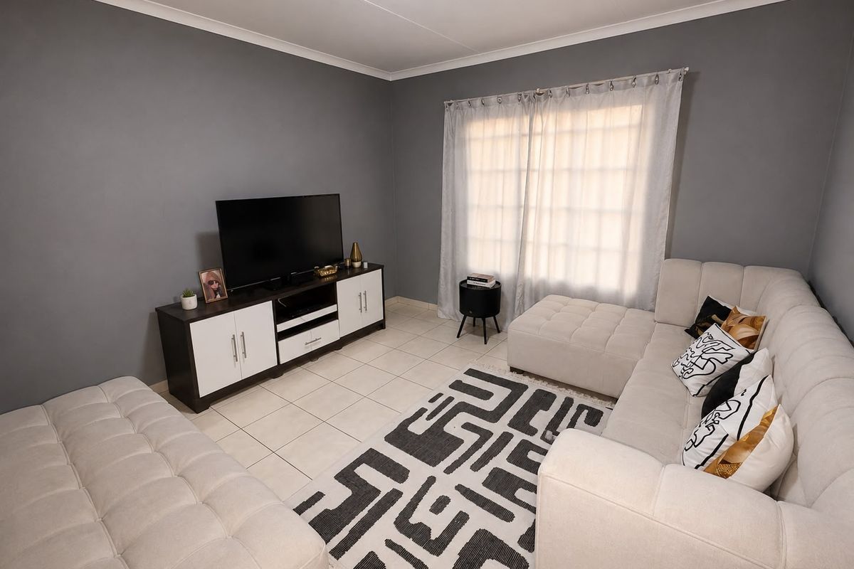 A well-maintained living room featuring neutral grey walls, tiled flooring, and a coved ceiling, providing a comfortable and functional space.
