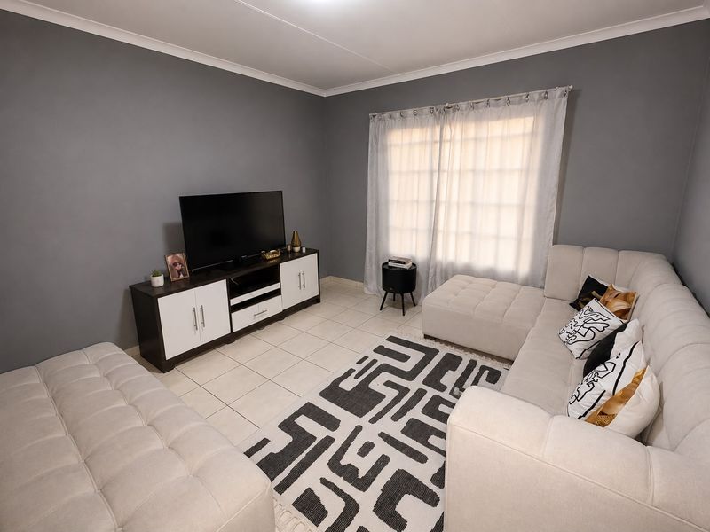 A well-maintained living room featuring neutral grey walls, tiled flooring, and a coved ceiling, providing a comfortable and functional space.