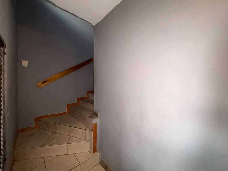 A staircase area featuring tiled steps and a wooden handrail, leading to an upper level.