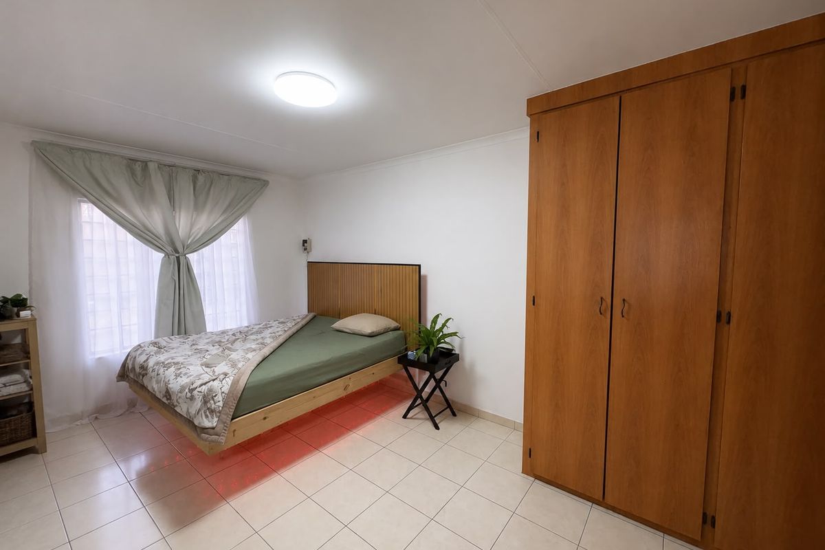 A bedroom featuring tiled flooring, a built-in wooden wardrobe, and a ceiling light fixture.