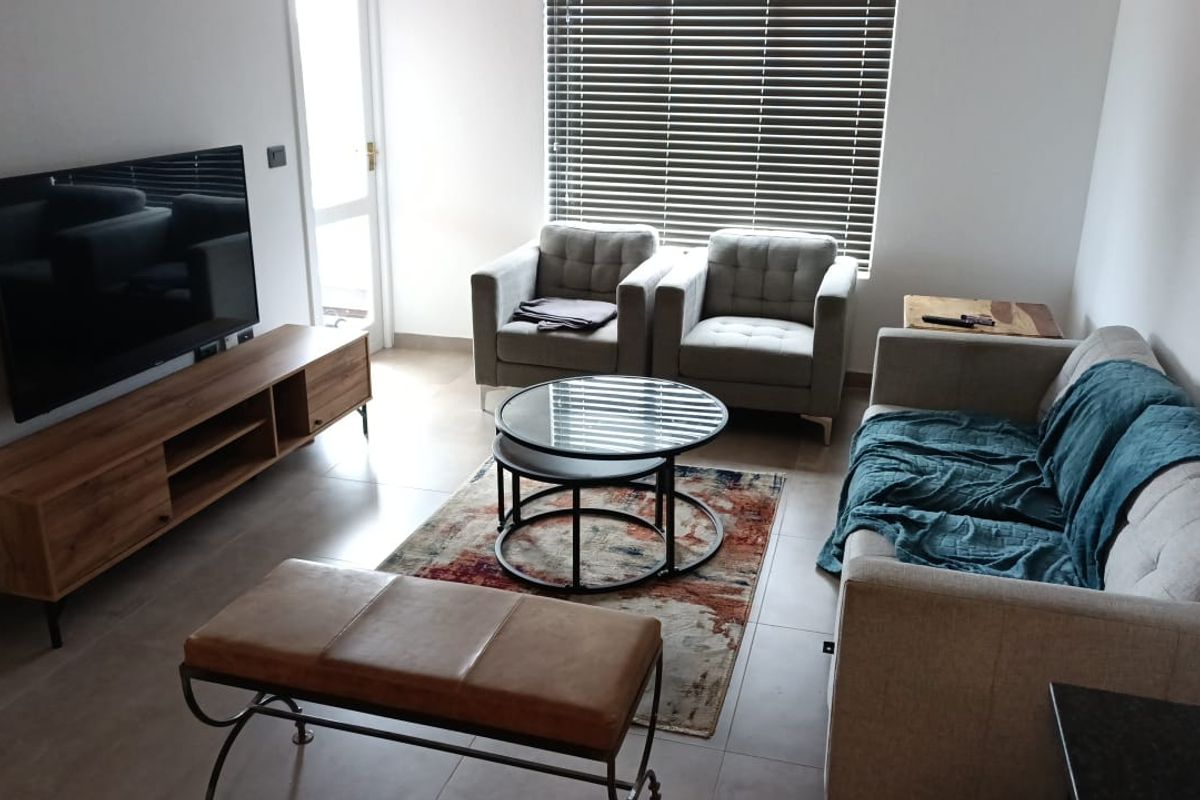 A well-lit living room featuring neutral tiled flooring and venetian blinds, providing a comfortable and functional space.