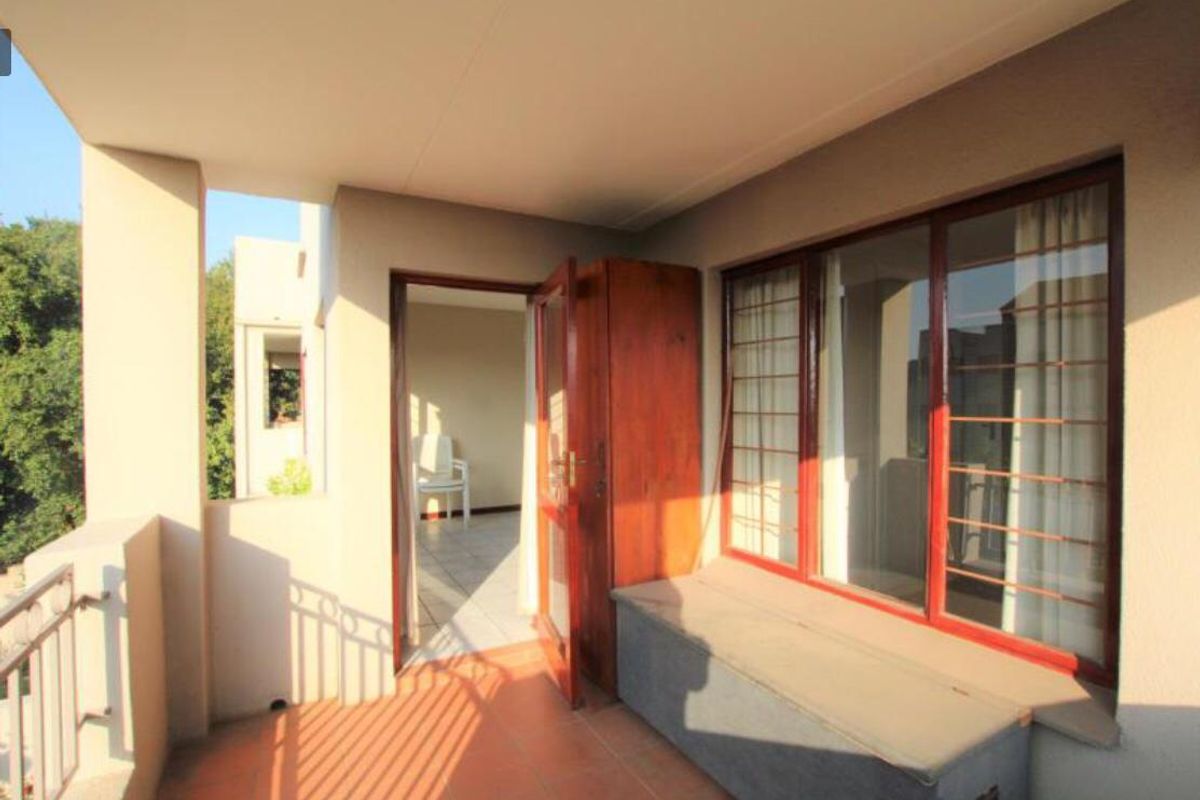 A covered balcony featuring tiled flooring, metal security bars on windows, and a built-in bench, providing a functional outdoor space.