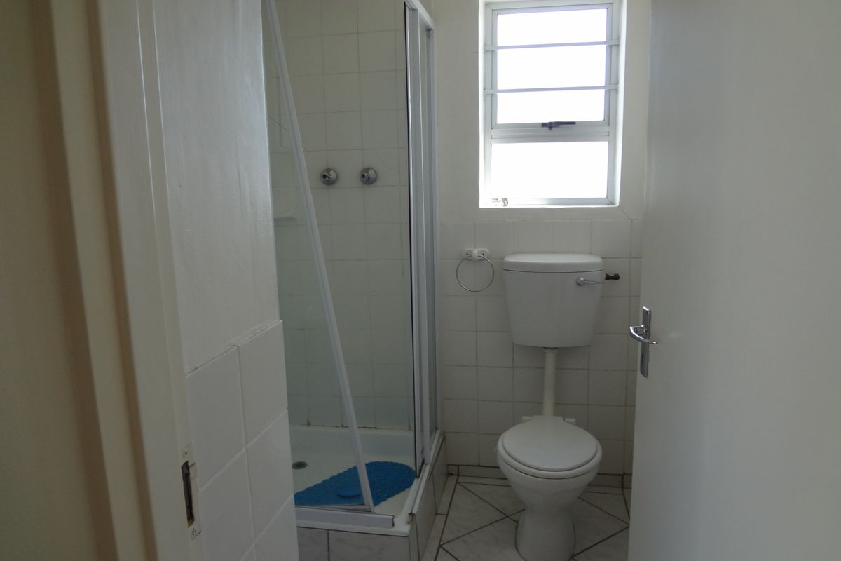 A compact bathroom featuring a shower enclosure, toilet, and tiled finishes, offering a functional space ready for modernization.