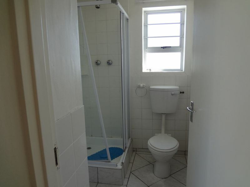 A compact bathroom featuring a shower enclosure, toilet, and tiled finishes, offering a functional space ready for modernization.