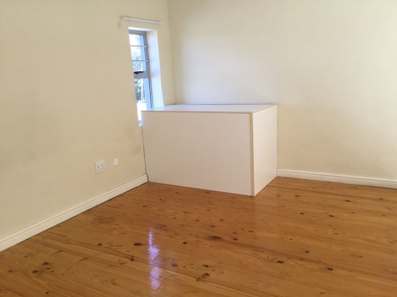 An empty bedroom featuring polished timber flooring, neutral walls, and a window, providing a blank canvas for personalization.