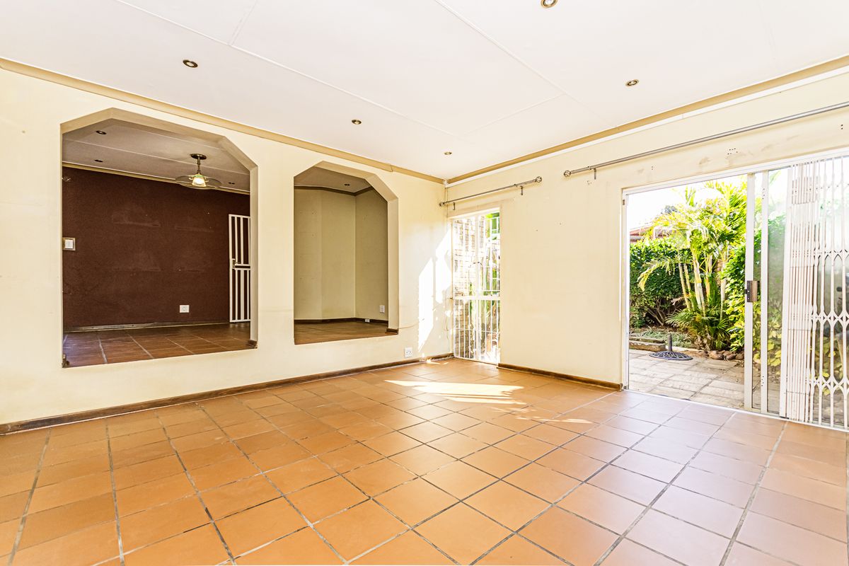 Spacious, empty living area featuring terracotta floor tiles, recessed lighting, and direct access to the rear garden through a sliding glass door.