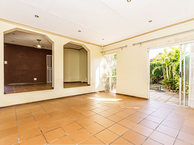 Spacious, empty living area featuring terracotta floor tiles, recessed lighting, and direct access to the rear garden through a sliding glass door.