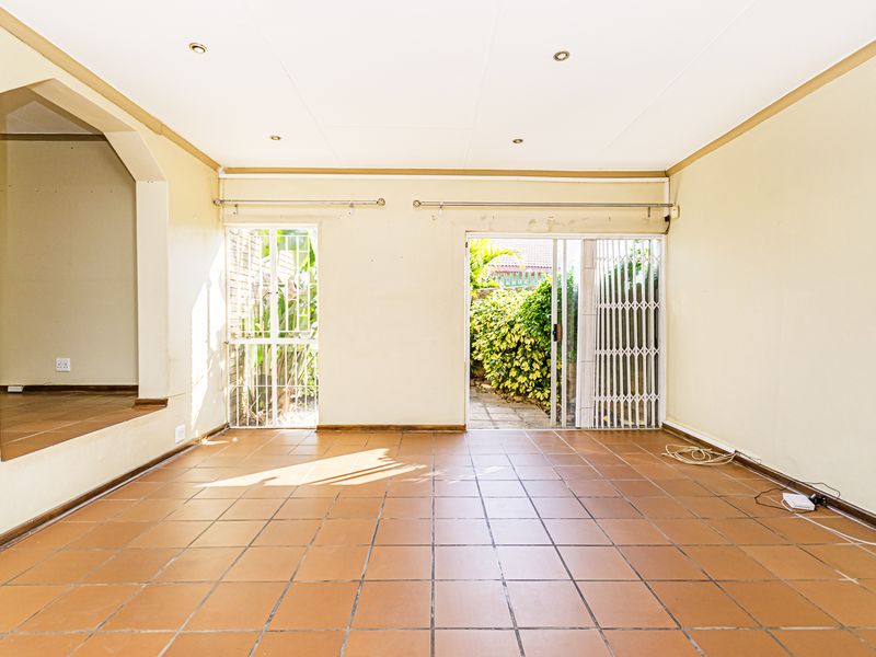 An empty living room featuring tiled flooring, recessed lighting, and a sliding glass door providing access to the outdoor area.