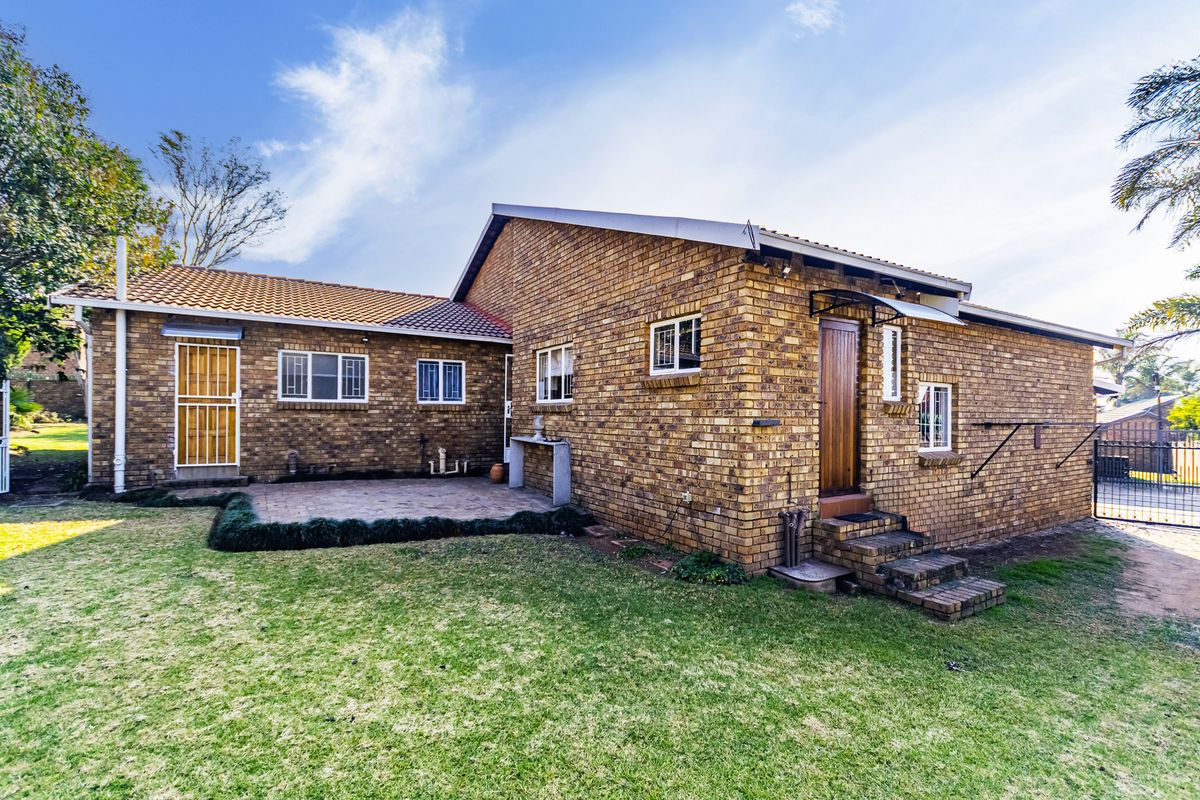 Rear view of the duet property featuring a facebrick facade, tiled roof, and a paved patio area leading into the garden.