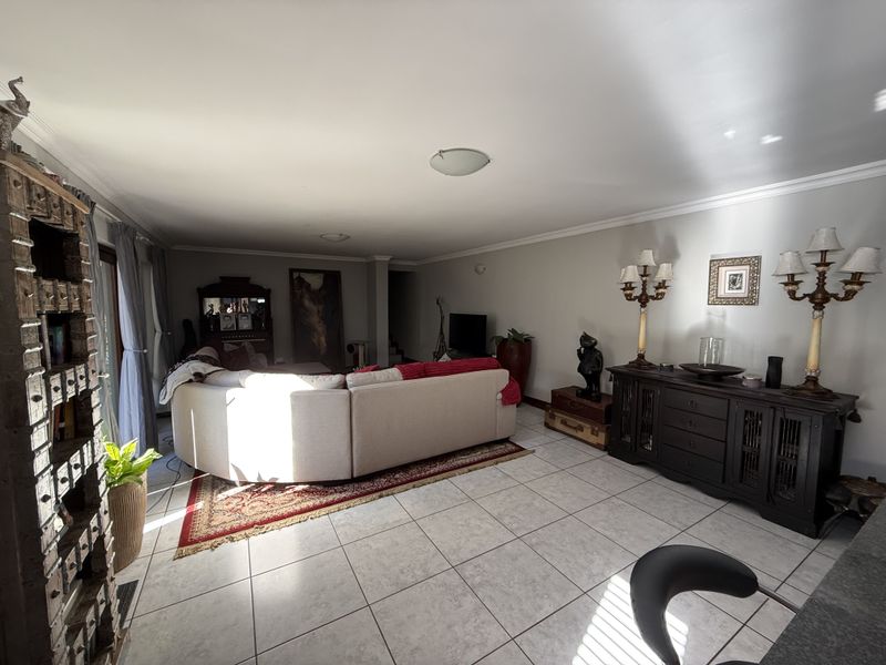 Spacious living room featuring neutral ceramic floor tiles, coved ceiling cornices, and large sliding glass doors providing access to the outdoor area.