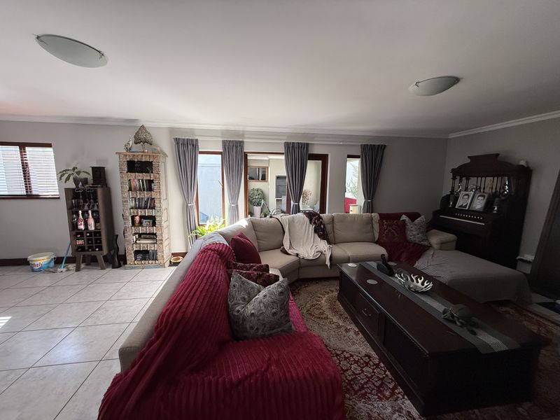 Spacious living room featuring tiled flooring, coved cornicing, and large sliding glass doors providing access to the outdoor area.