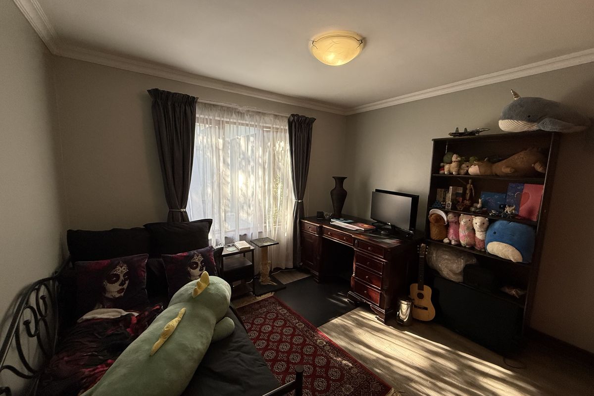 A bedroom featuring laminate flooring, ceiling cornice, and a central flush mount light fixture, offering a functional space with natural light.