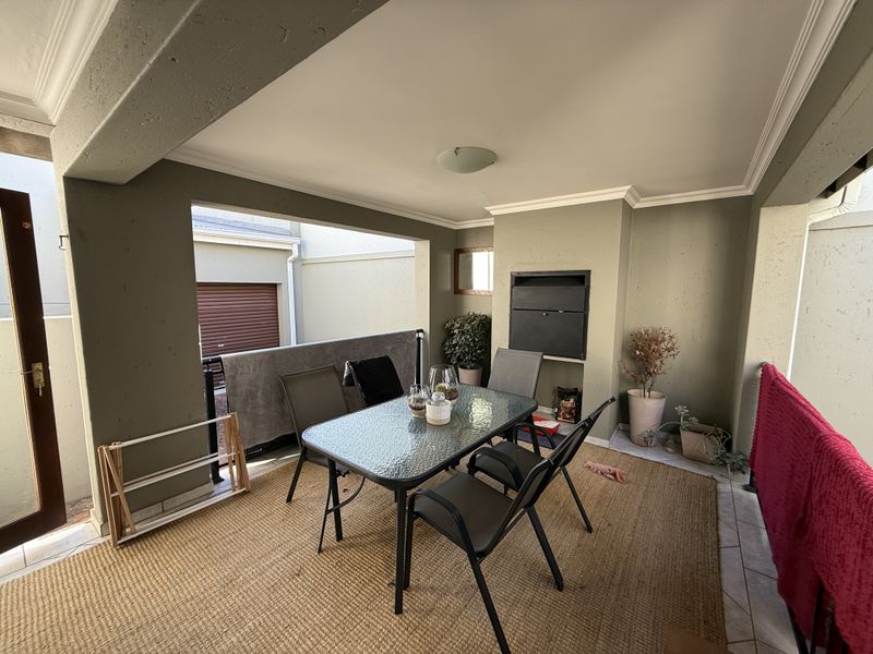 Covered patio area featuring a built-in braai, tiled flooring, and direct access to the exterior, providing a functional space for outdoor dining and entertaining.