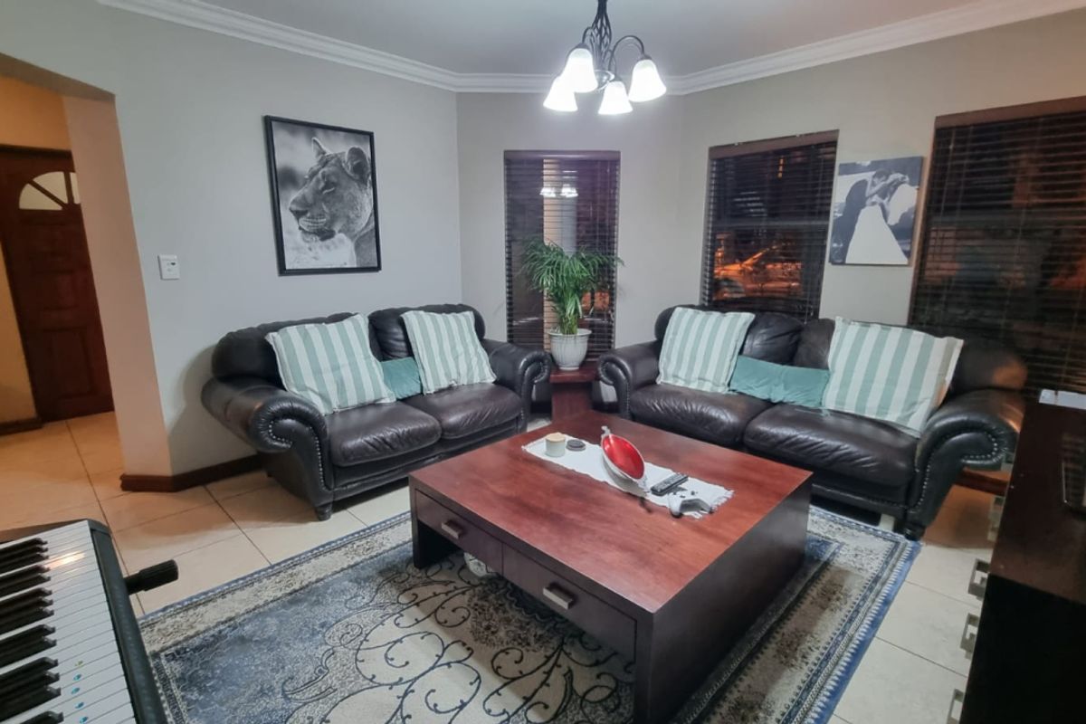 A comfortable living room featuring tiled flooring, cove cornicing, and venetian blinds, providing a functional and well-maintained space for relaxation.