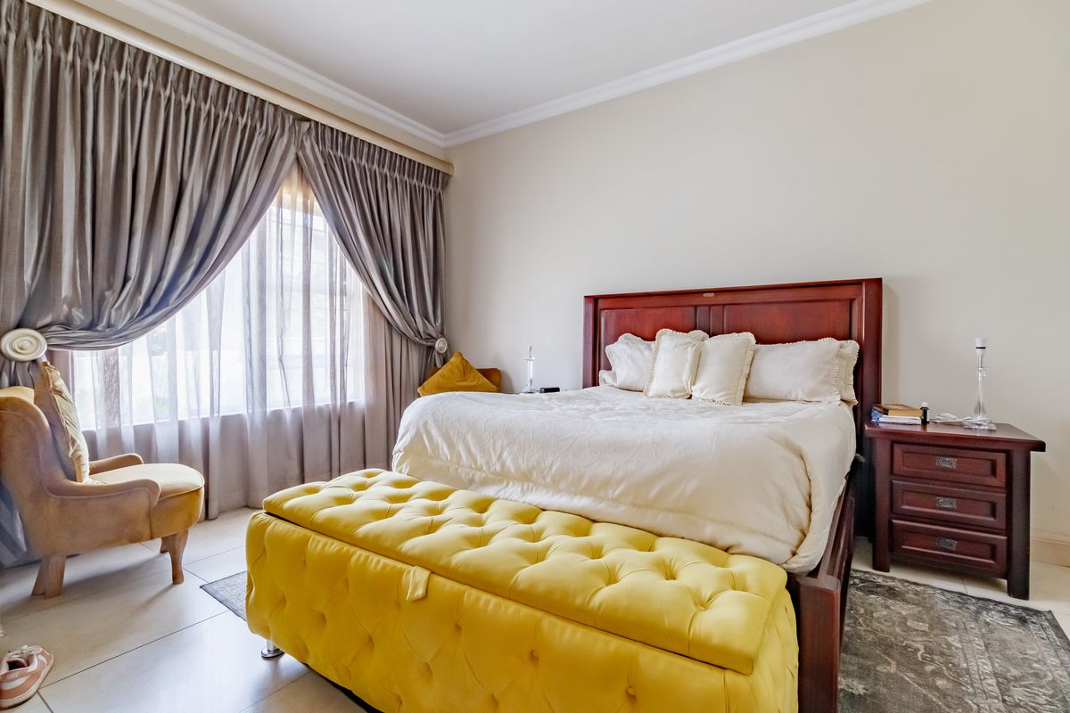 A well-maintained bedroom featuring tiled flooring, crown molding, and large windows with installed curtain tracks.
