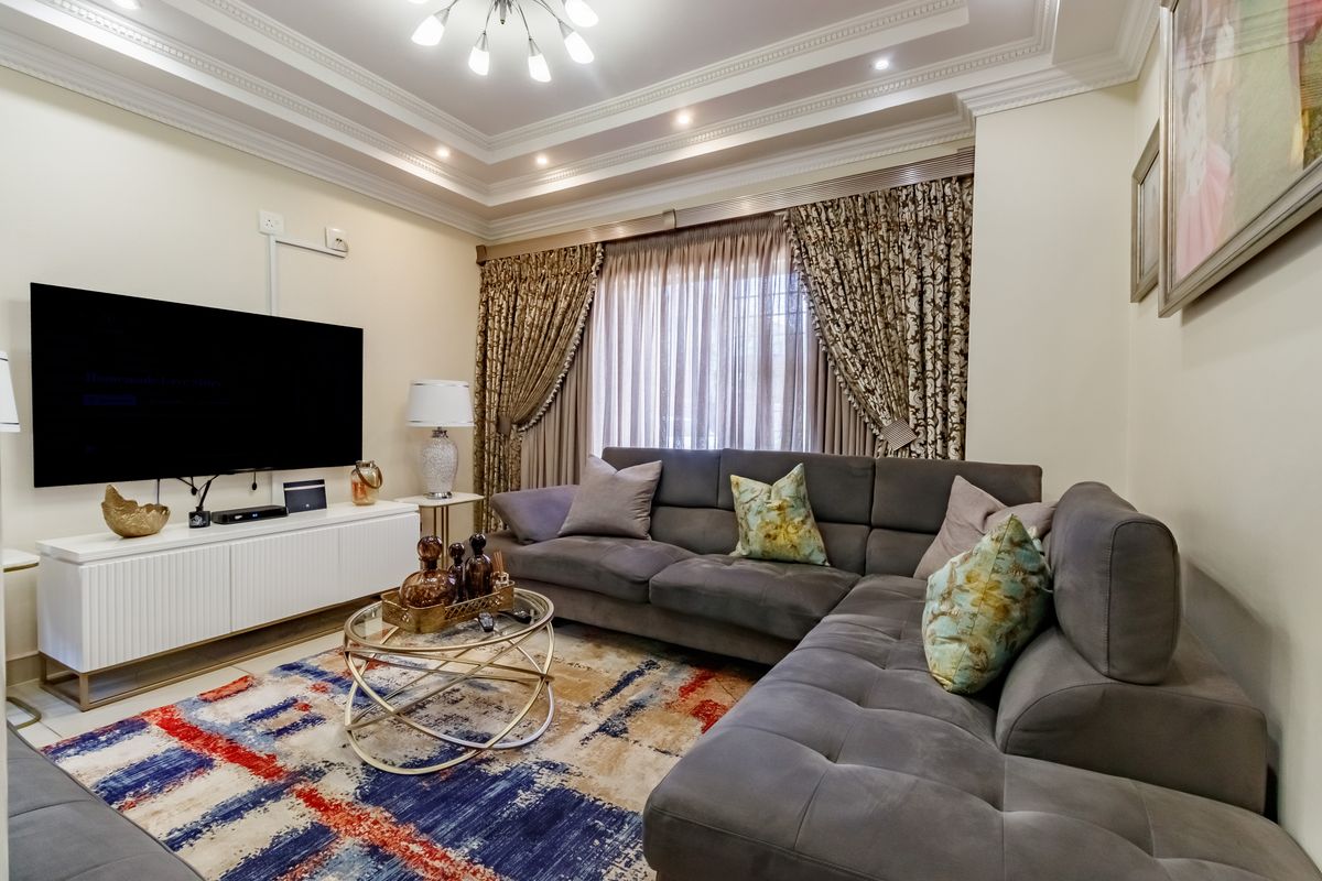 A well-maintained living room featuring a recessed tray ceiling with integrated cove lighting and crown molding.
