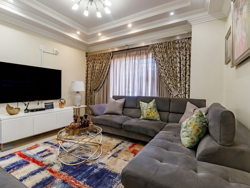 A well-maintained living room featuring a recessed tray ceiling with integrated cove lighting and crown molding.