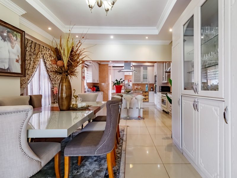 Spacious open-plan dining and kitchen area featuring modern cabinetry, a central island, tiled flooring, and elegant recessed ceiling lighting.