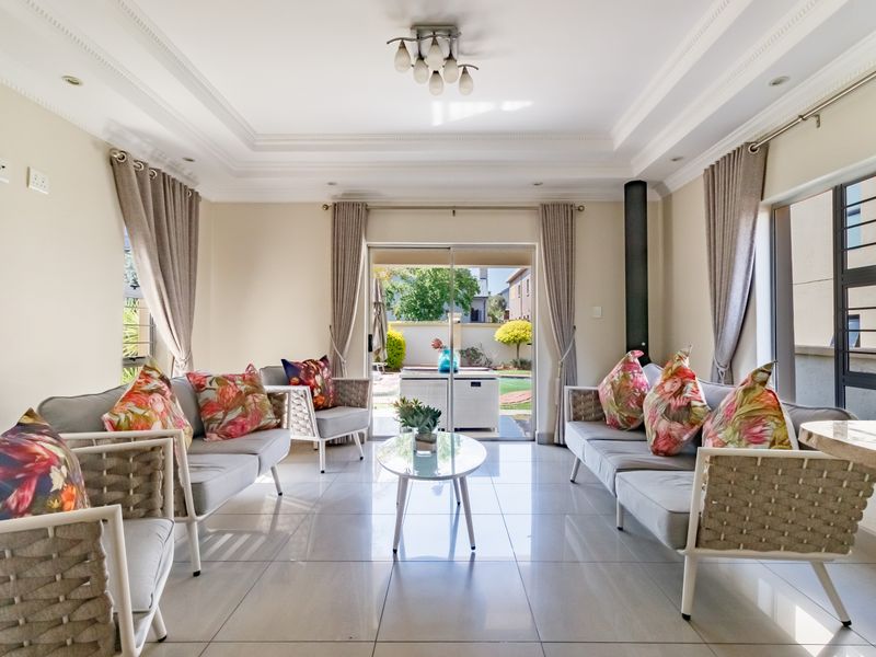 Bright and spacious living room featuring tiled floors, a modern freestanding fireplace, and large sliding doors providing seamless access to the outdoor patio area.