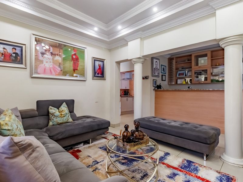 Spacious living room featuring decorative crown molding, recessed ceiling lighting, and a built-in bar area with integrated cabinetry.