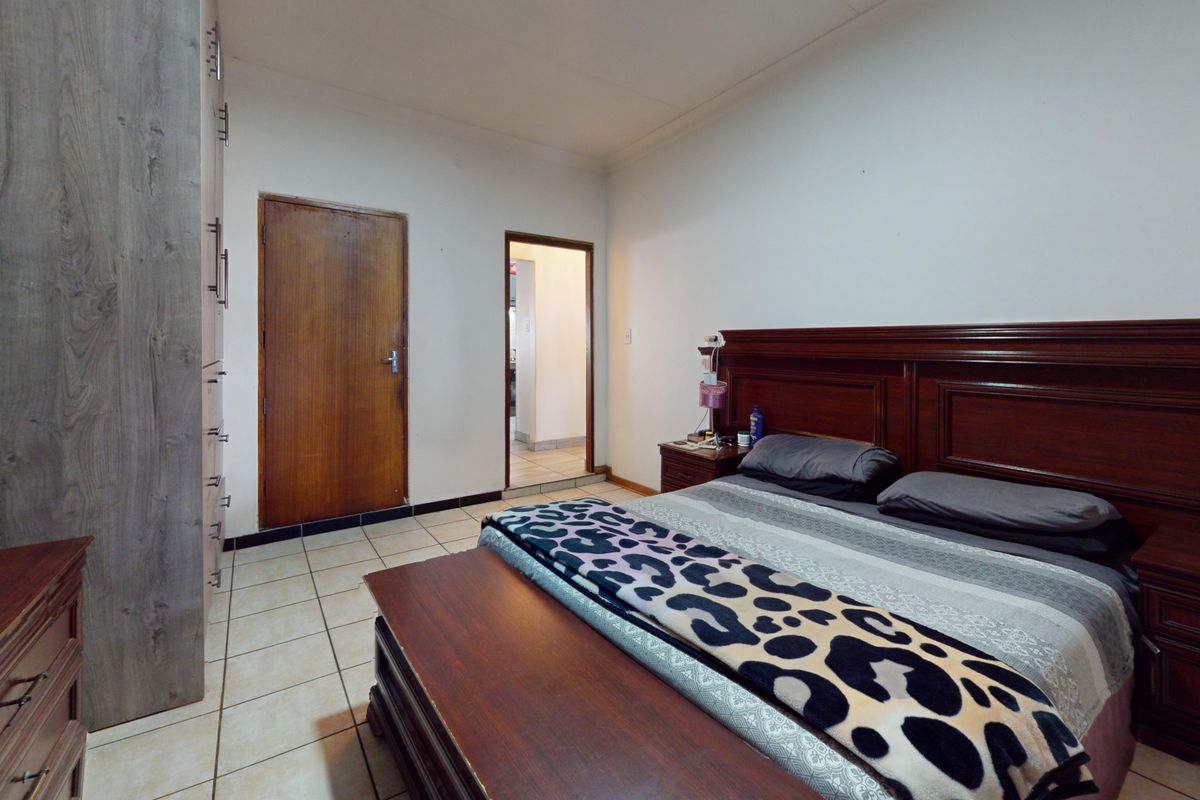 A functional bedroom featuring tiled flooring, a built-in wardrobe, and a wooden door leading to an adjacent space.