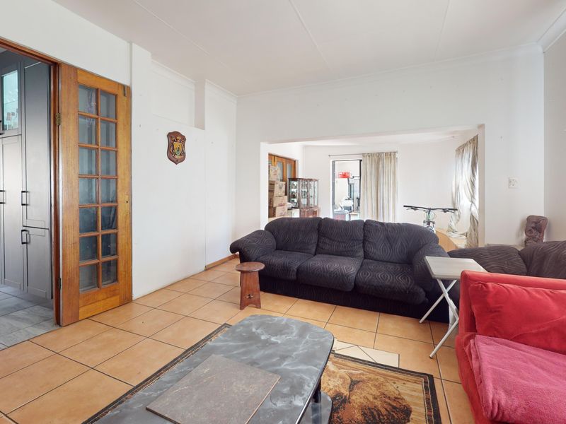 Open plan living area featuring tiled flooring and a timber framed glass door, connecting to adjacent kitchen and living spaces.