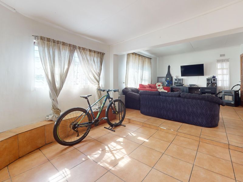 Open plan living area featuring tiled flooring and a raised platform section, providing a versatile space for lounge or dining arrangements.