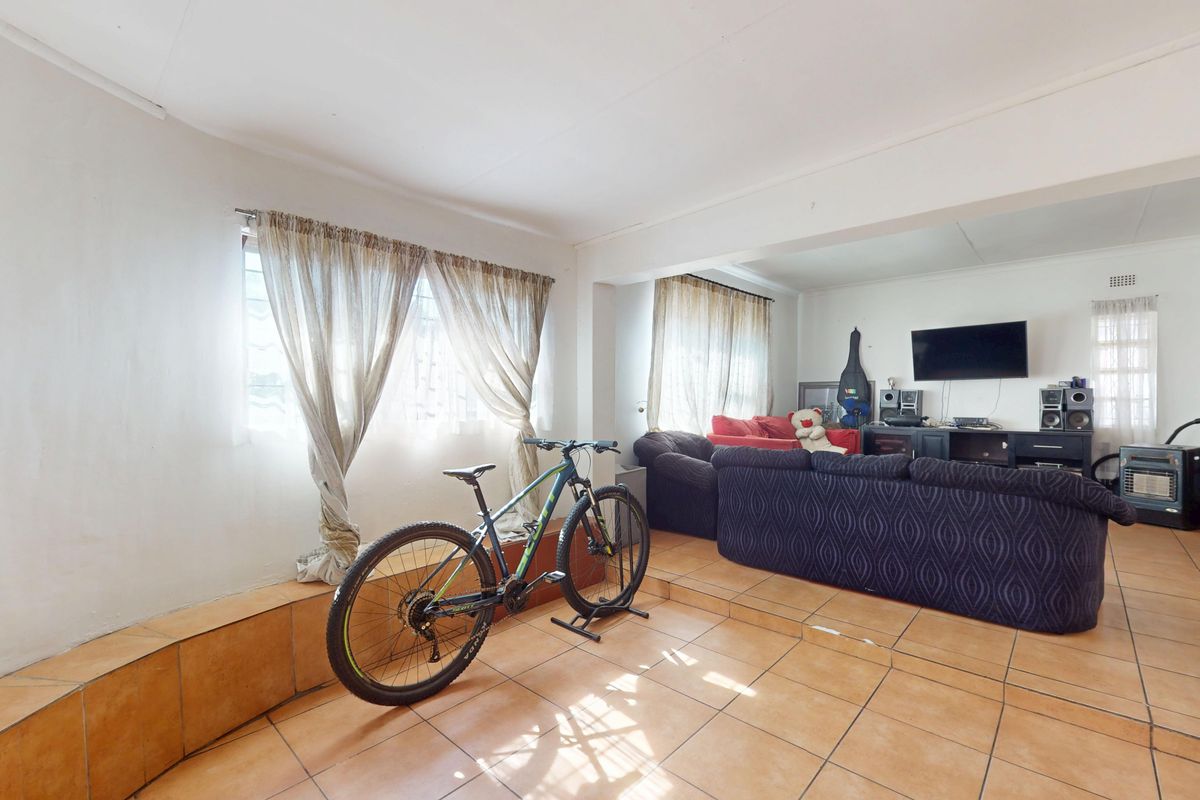 Spacious living area featuring tiled flooring and a raised platform section, offering a versatile layout for comfortable family living.