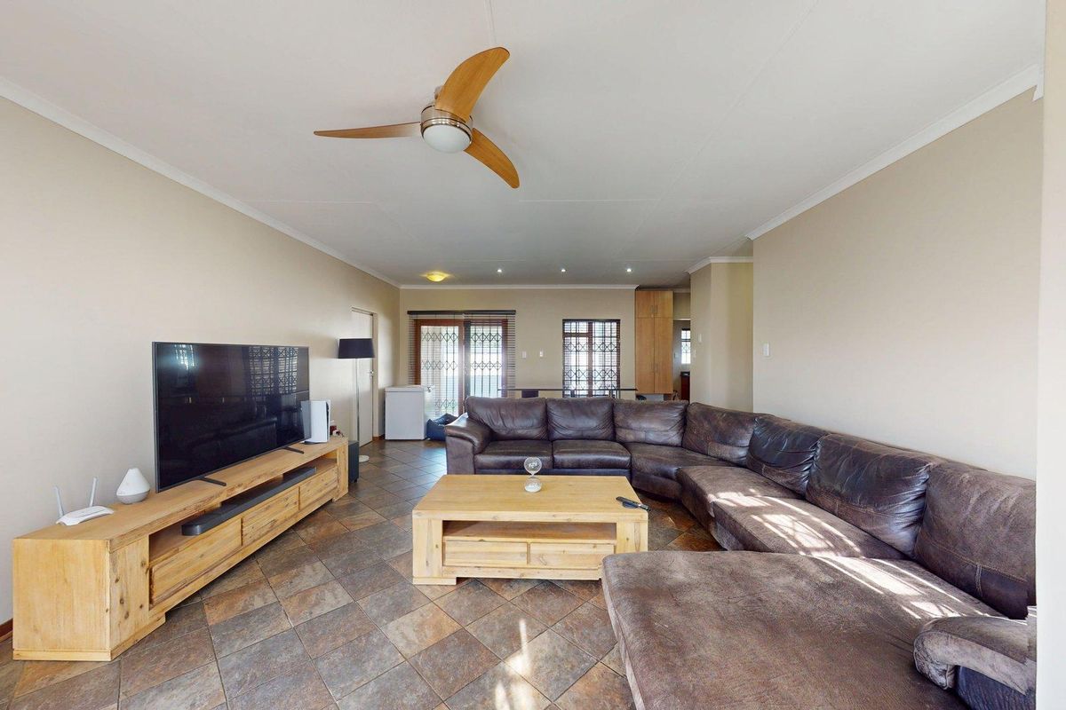 Spacious living room featuring tiled flooring, a ceiling fan, and sliding glass doors leading to the exterior, providing a comfortable and functional living space.
