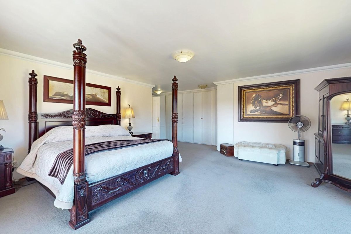 Spacious bedroom featuring neutral wall finishes, fitted built-in cupboards, and carpeted flooring, offering a comfortable and functional living space.