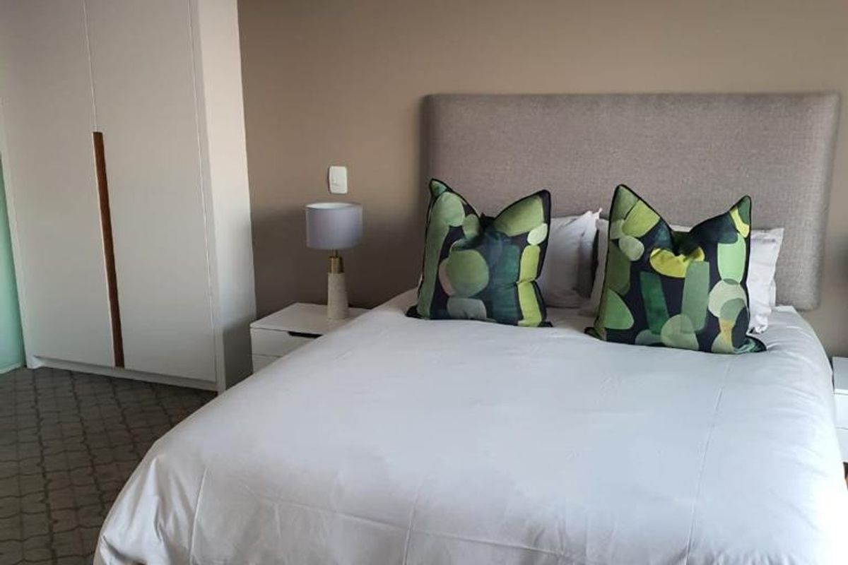 A well-maintained bedroom featuring neutral wall tones, patterned carpeting, and a large built-in wardrobe for ample storage.