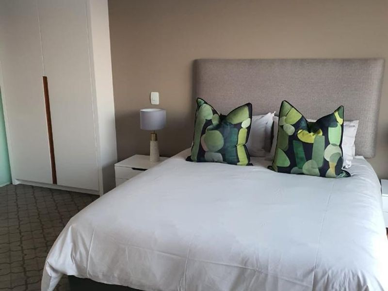 A well-maintained bedroom featuring neutral wall tones, patterned carpeting, and a large built-in wardrobe for ample storage.
