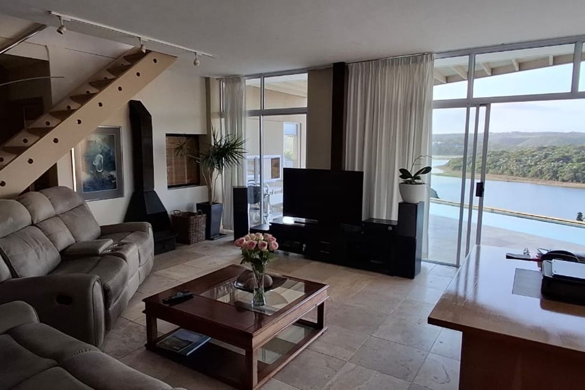 Spacious living area featuring a fireplace, staircase, and large sliding glass doors that open to a scenic river view.