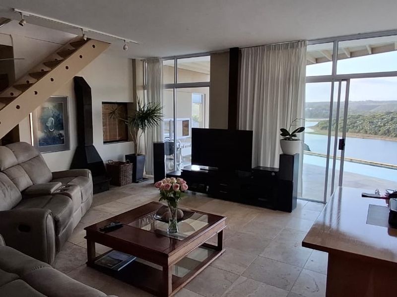 Spacious living area featuring a fireplace, staircase, and large sliding glass doors that open to a scenic river view.