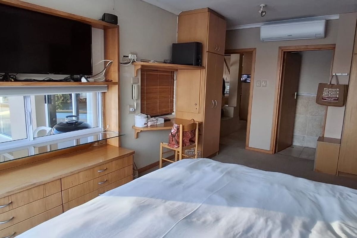 Bedroom featuring extensive built-in cabinetry, a dedicated desk area, and a wall-mounted air conditioning unit.