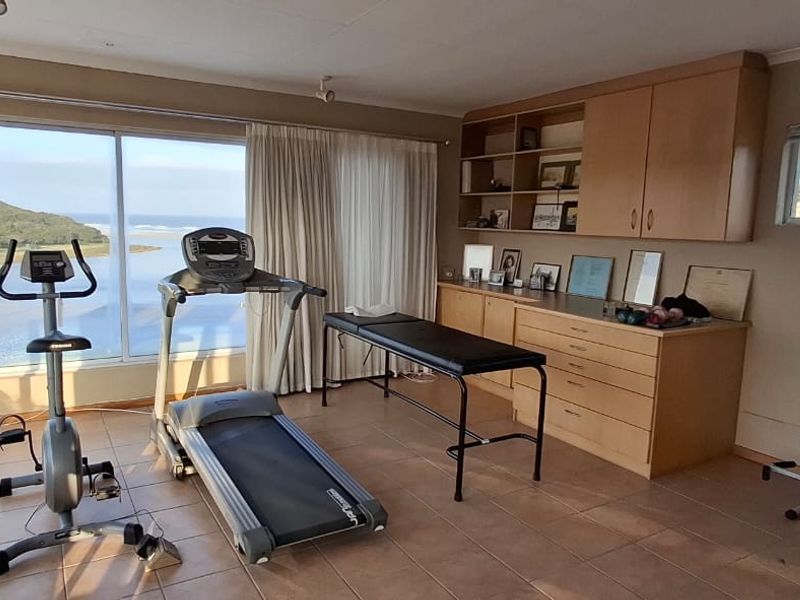 A bright gym space featuring built-in cabinetry, tiled flooring, and large windows offering scenic views of the surrounding landscape.