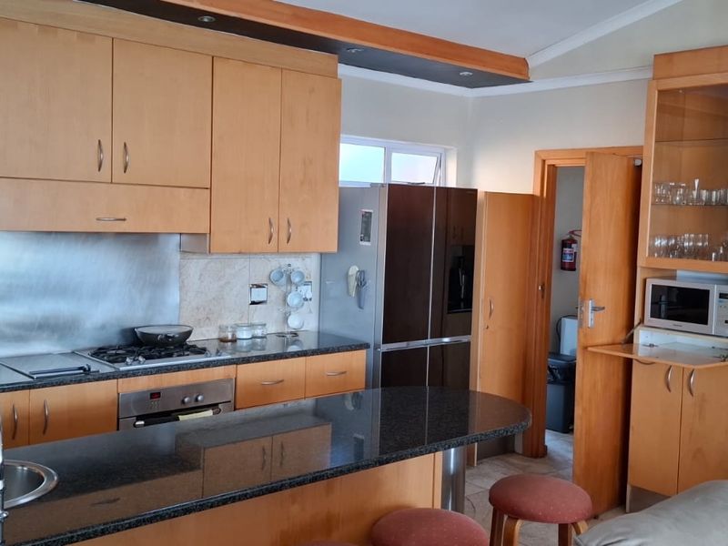 A functional kitchen featuring light wood cabinetry, granite countertops, a gas hob, and a breakfast bar, offering ample storage and workspace.