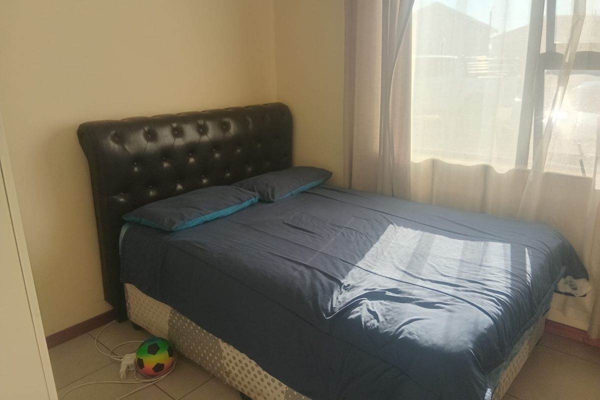 A functional bedroom featuring tiled flooring and a large window that allows for natural light.