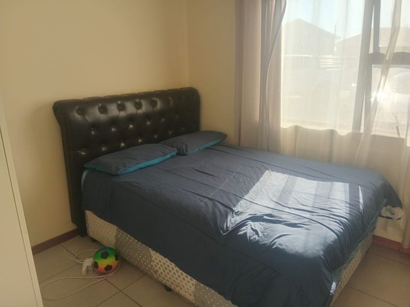 A functional bedroom featuring tiled flooring and a large window that allows for natural light.