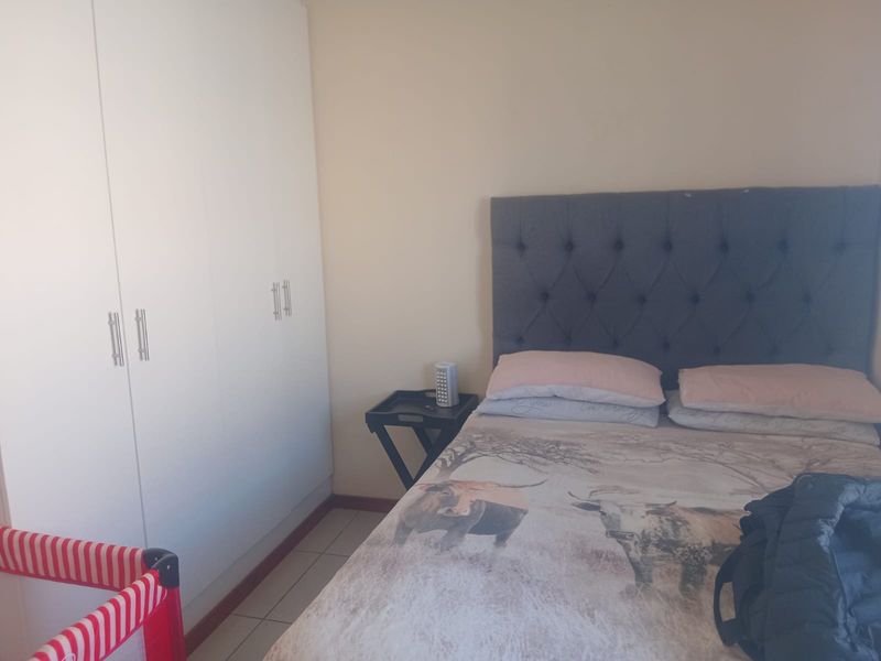 A functional bedroom featuring built-in cupboards and tiled flooring, providing a practical space for rest and storage.