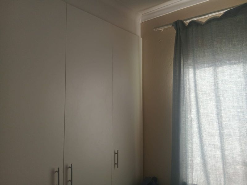 A bedroom corner featuring built-in white cupboards and decorative cornice detailing.