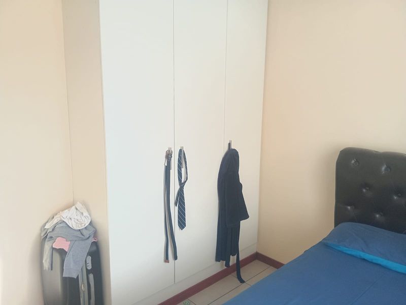 A bedroom featuring a white built-in wardrobe and tiled flooring.