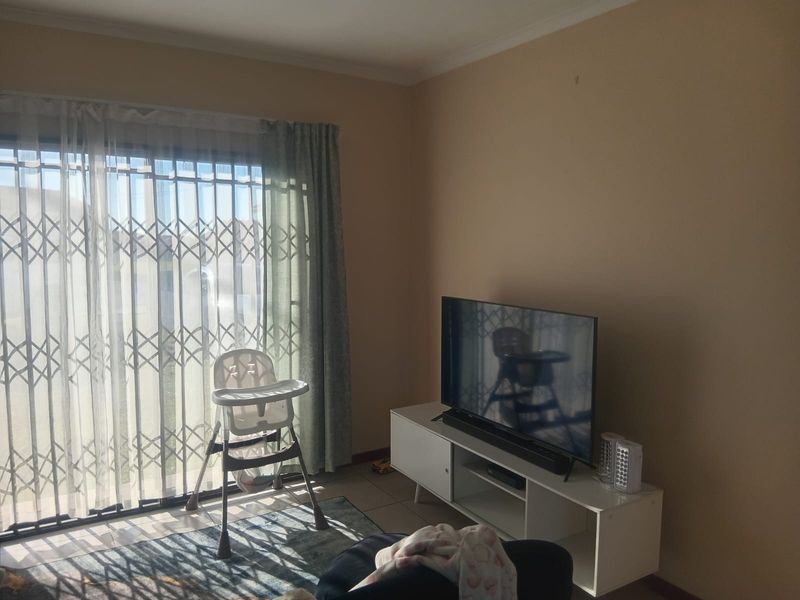 A living room featuring tiled flooring, a sliding door with a security gate, and neutral wall finishes.