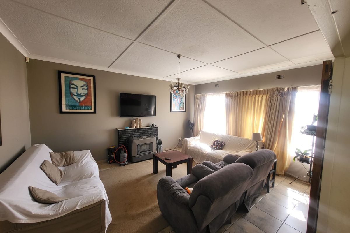 A living room featuring a fireplace, tiled ceiling, and a combination of carpet and tiled flooring, offering a functional space for relaxation.