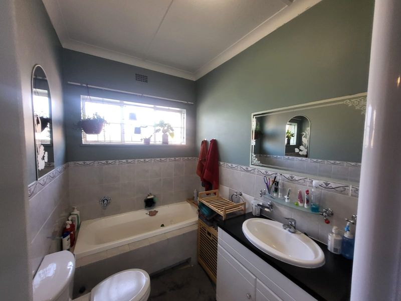 A functional bathroom featuring a built-in bathtub, a vanity unit with an integrated sink, and tiled wall accents.
